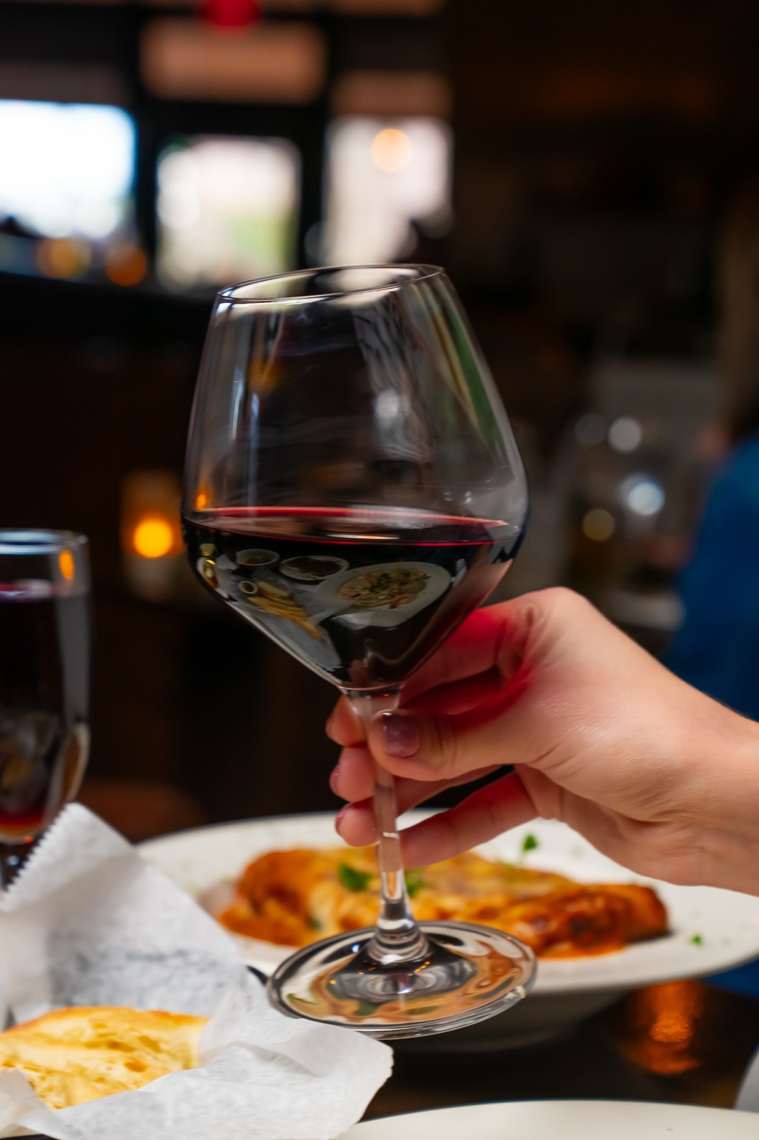 A glass of red wine raised over dinner at Sophia's